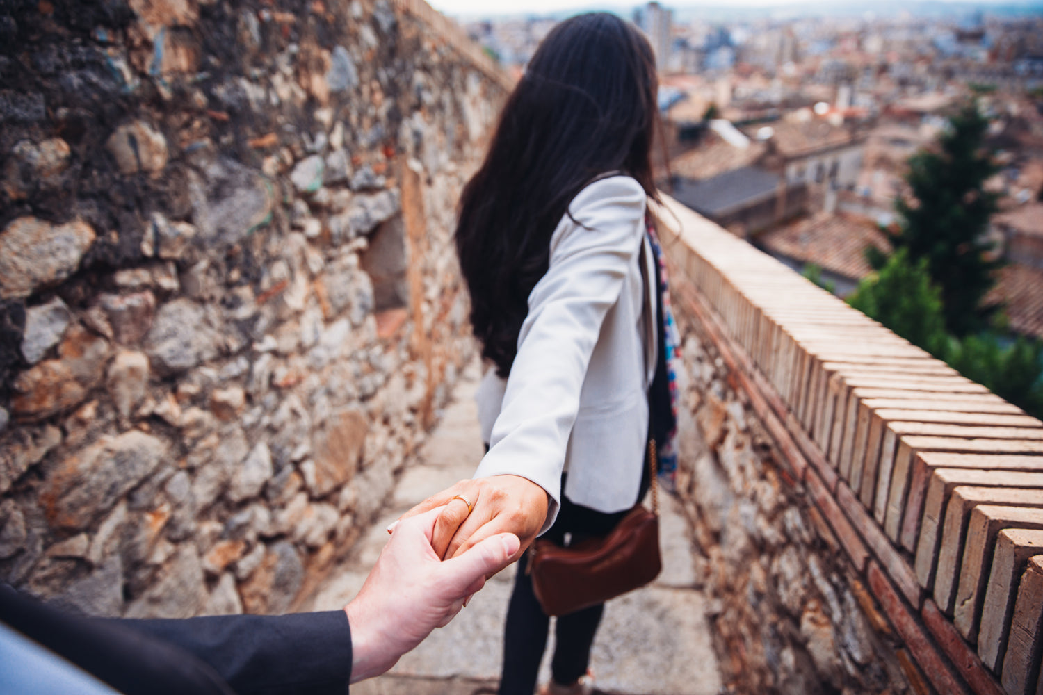 A woman in full frame reaching her hand and arm back to hold a man's hand from behind the camera
